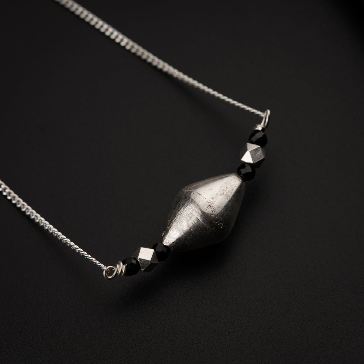 a silver necklace with a black bead hanging from it
