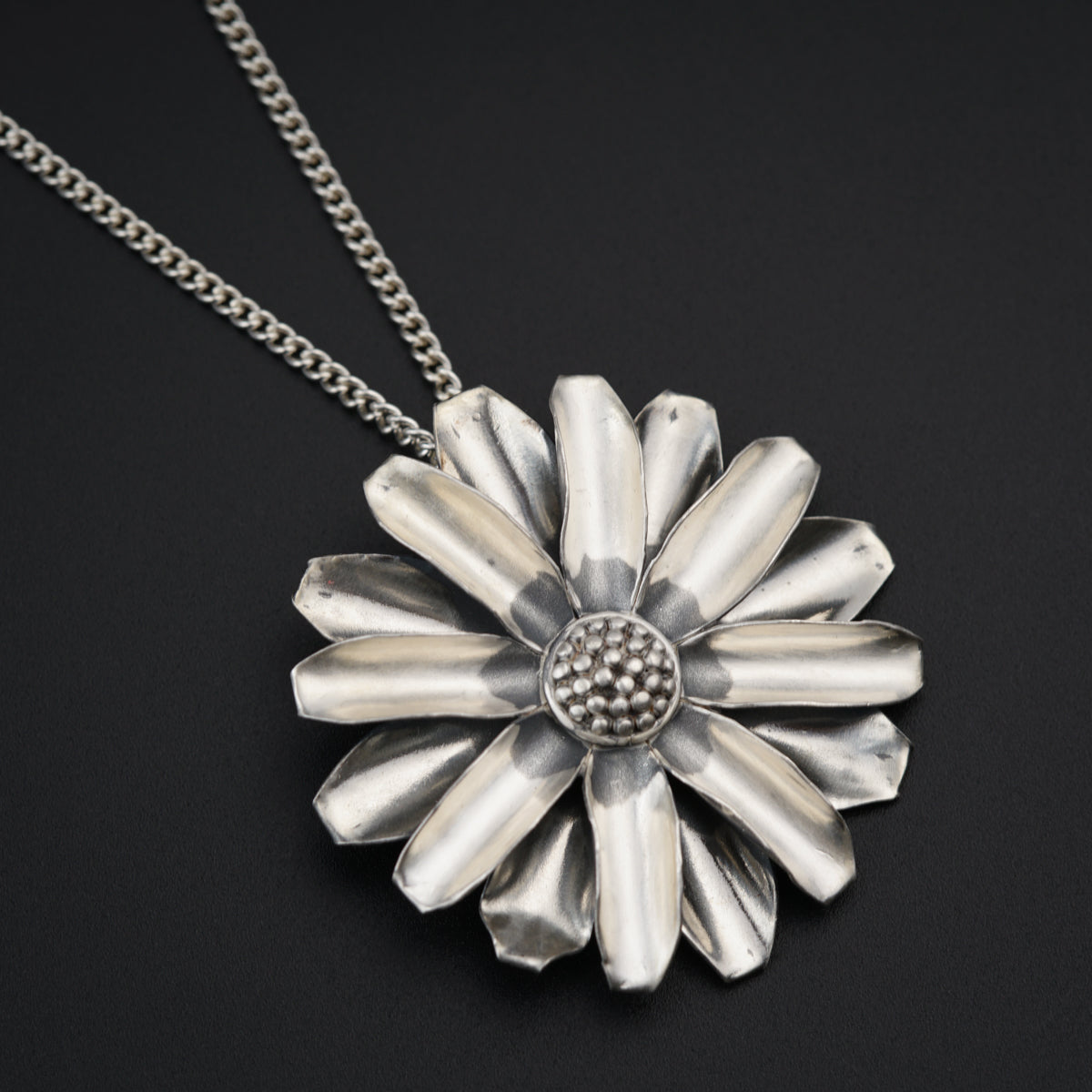 a silver flower pendant on a chain