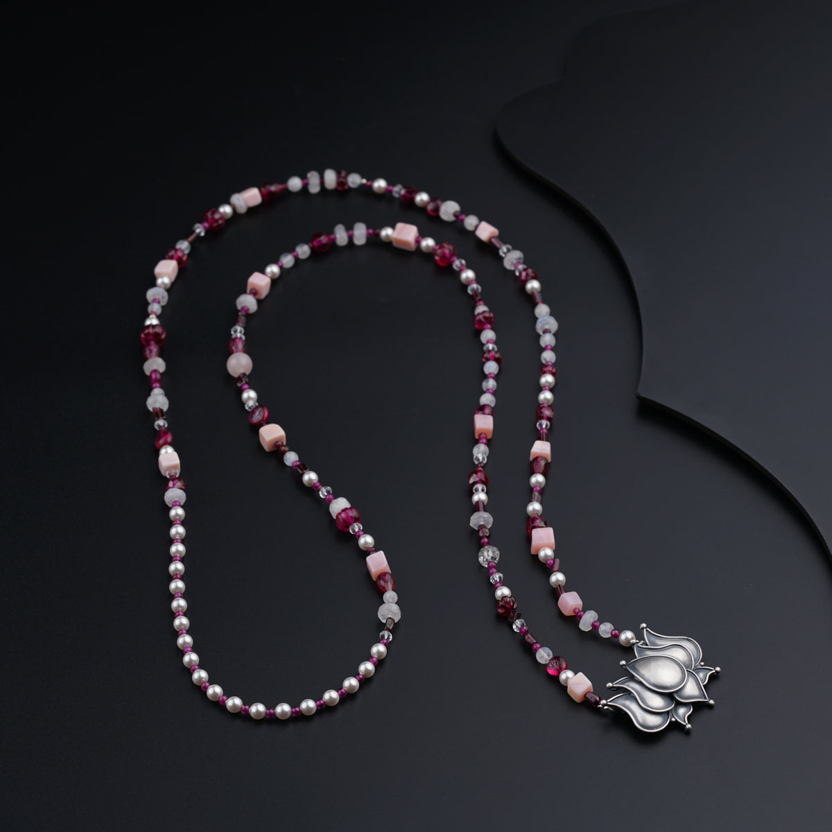a beaded necklace with a silver cross on it