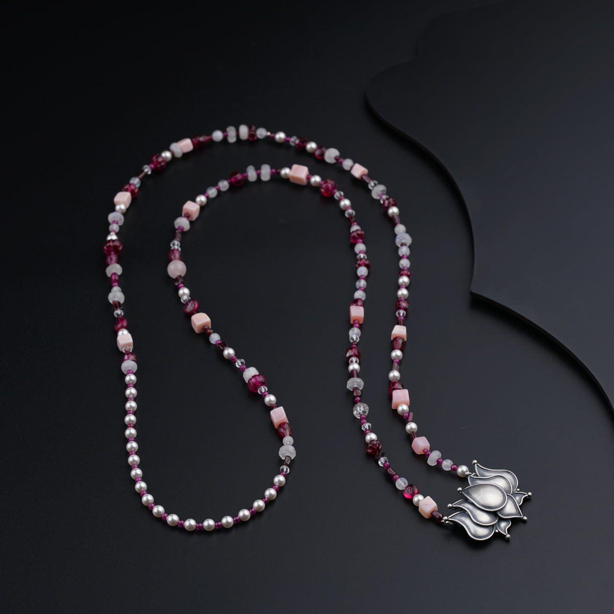 a beaded necklace with a silver cross on it