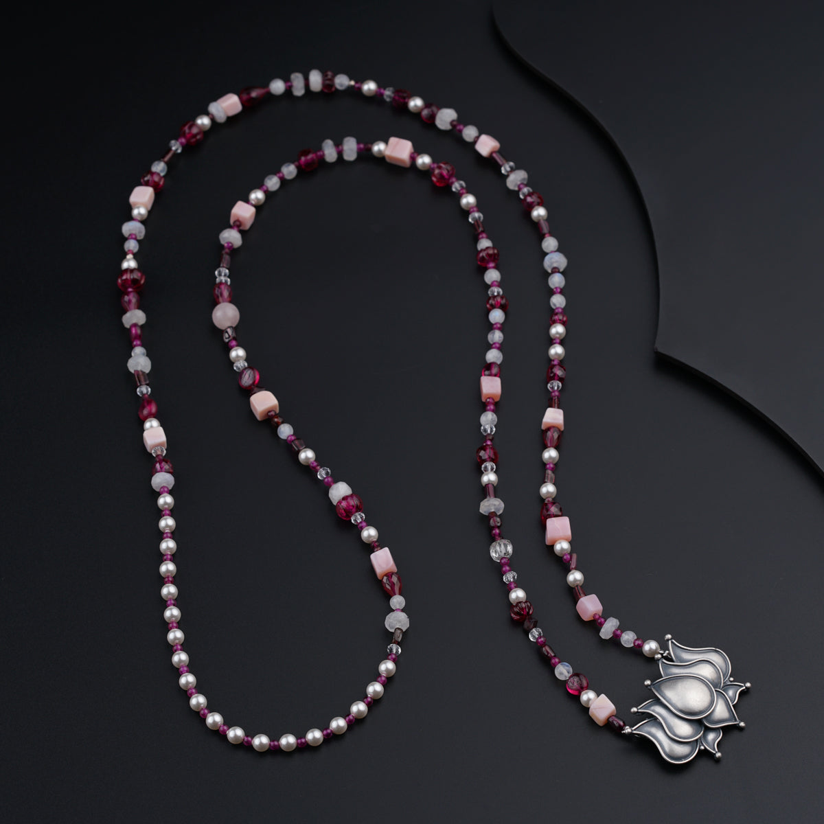 a long beaded necklace with a silver pendant