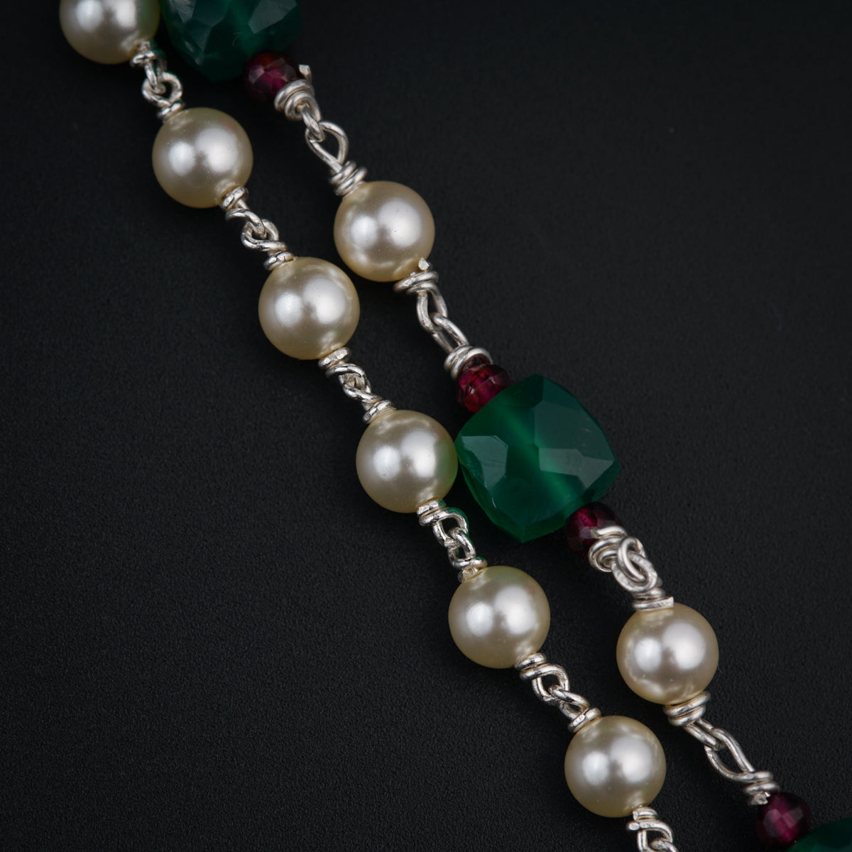 a close up of a necklace with pearls and beads