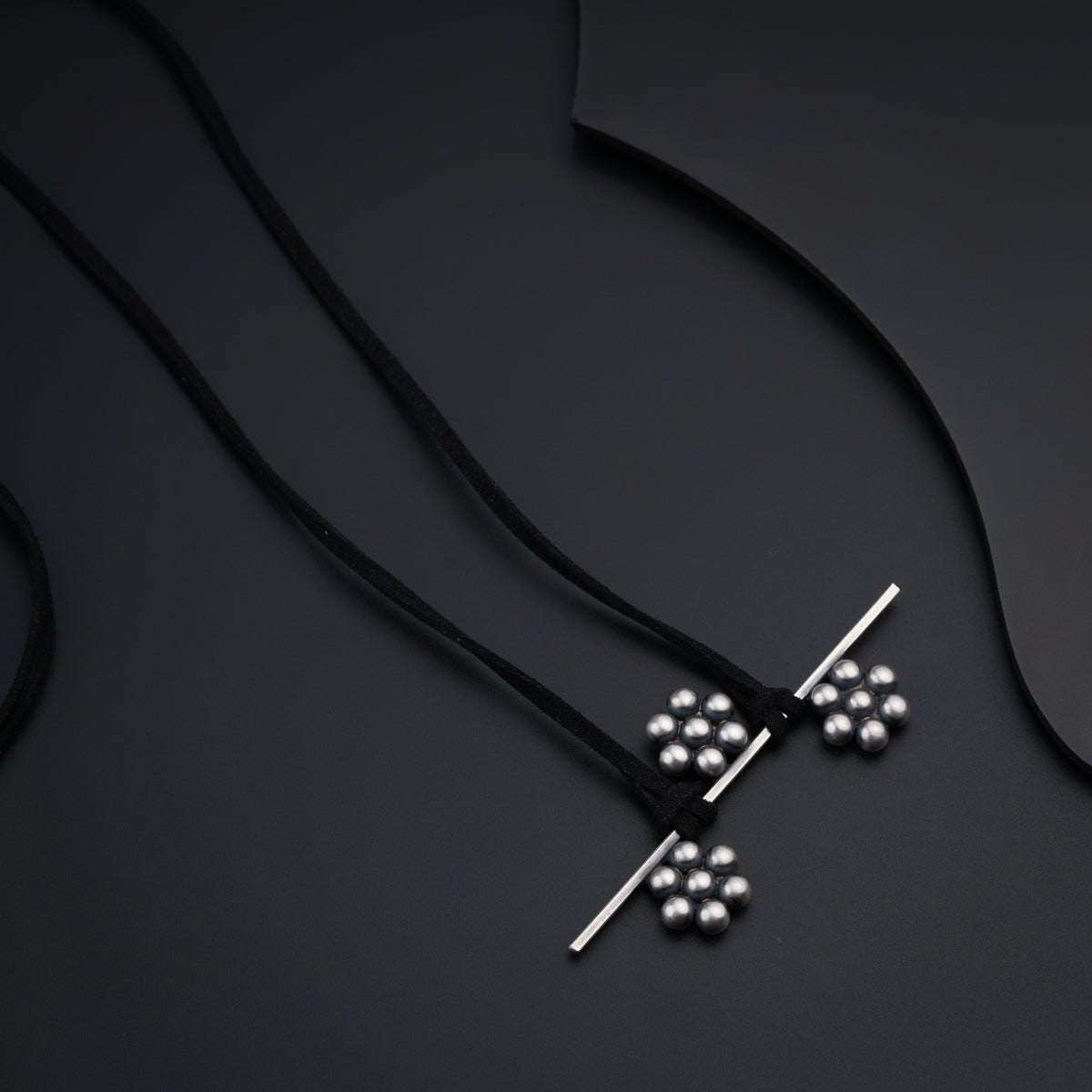 a necklace with four balls on a black background