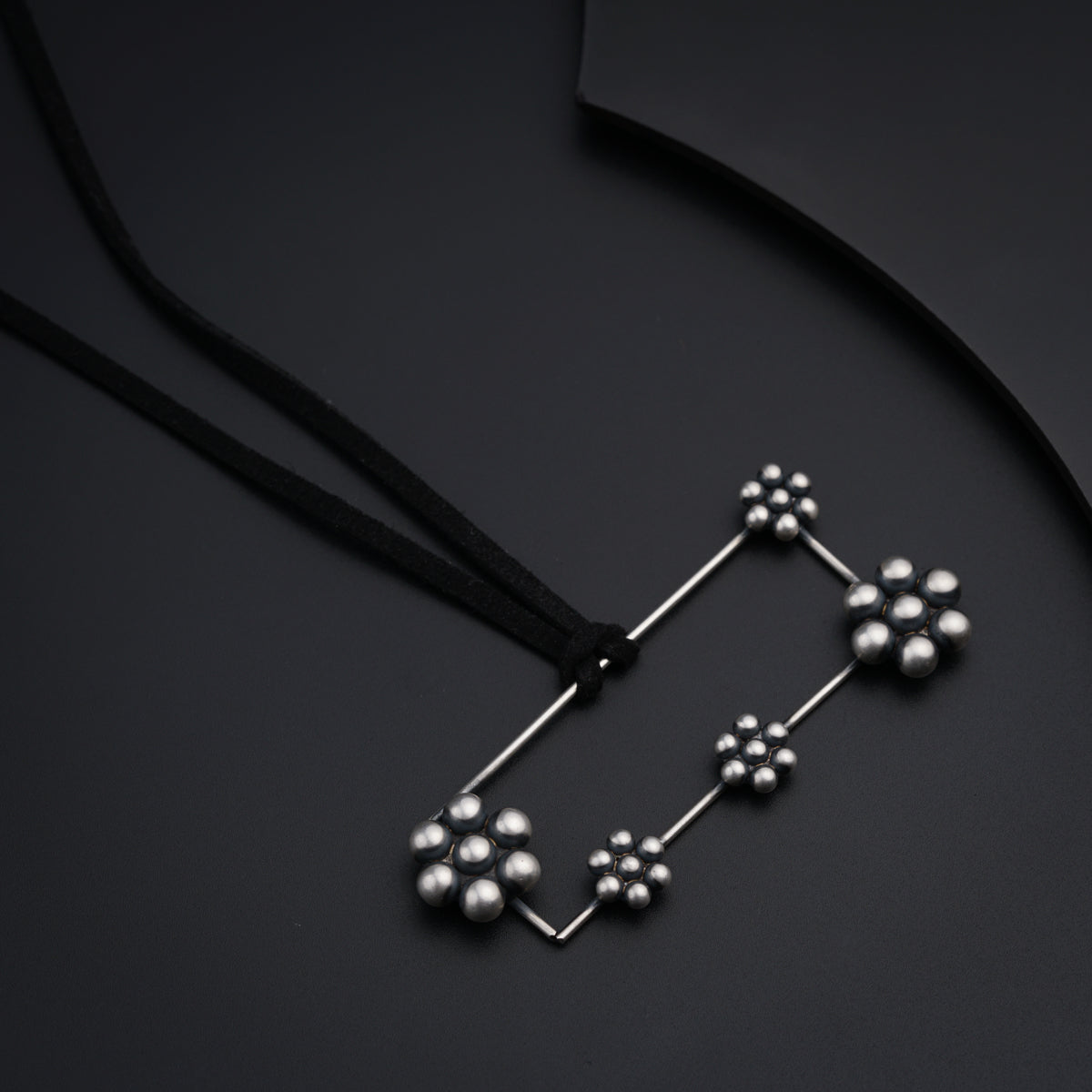 a black necklace with silver balls on a black background