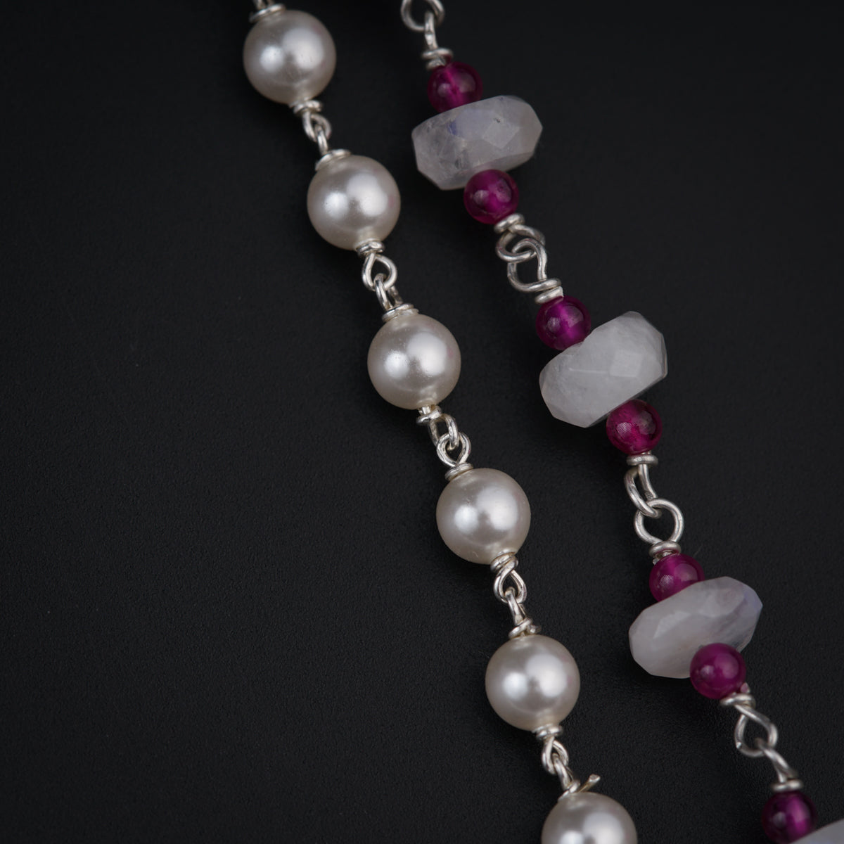 a close up of a necklace with pearls and beads