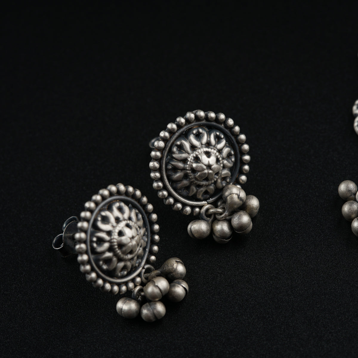 a pair of silver earrings on a black background