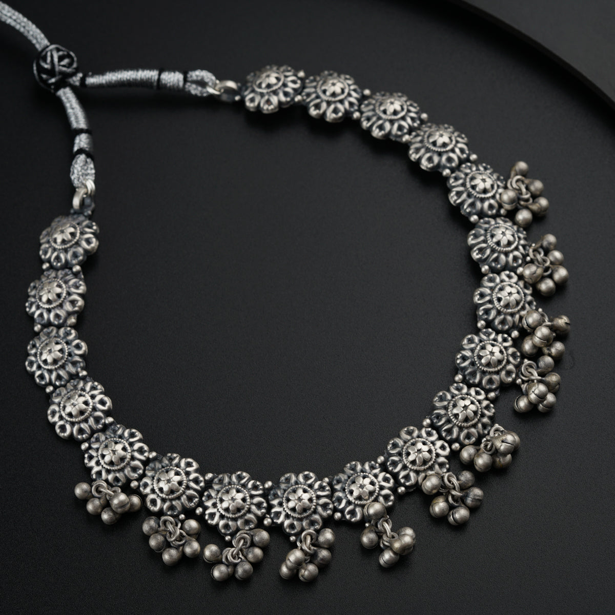 a silver necklace on a black surface