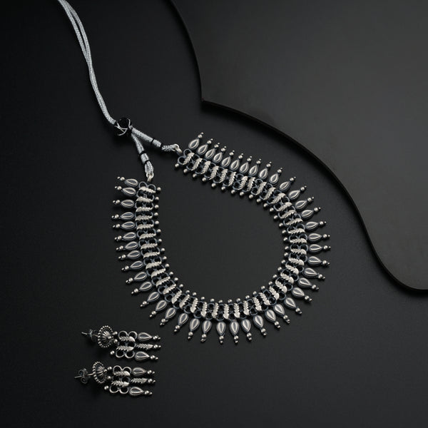 a silver necklace and matching earrings on a black surface