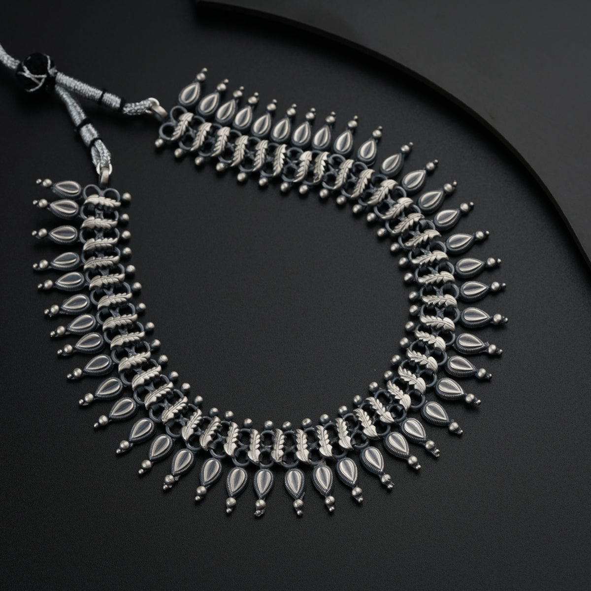 a black and silver necklace on a black surface