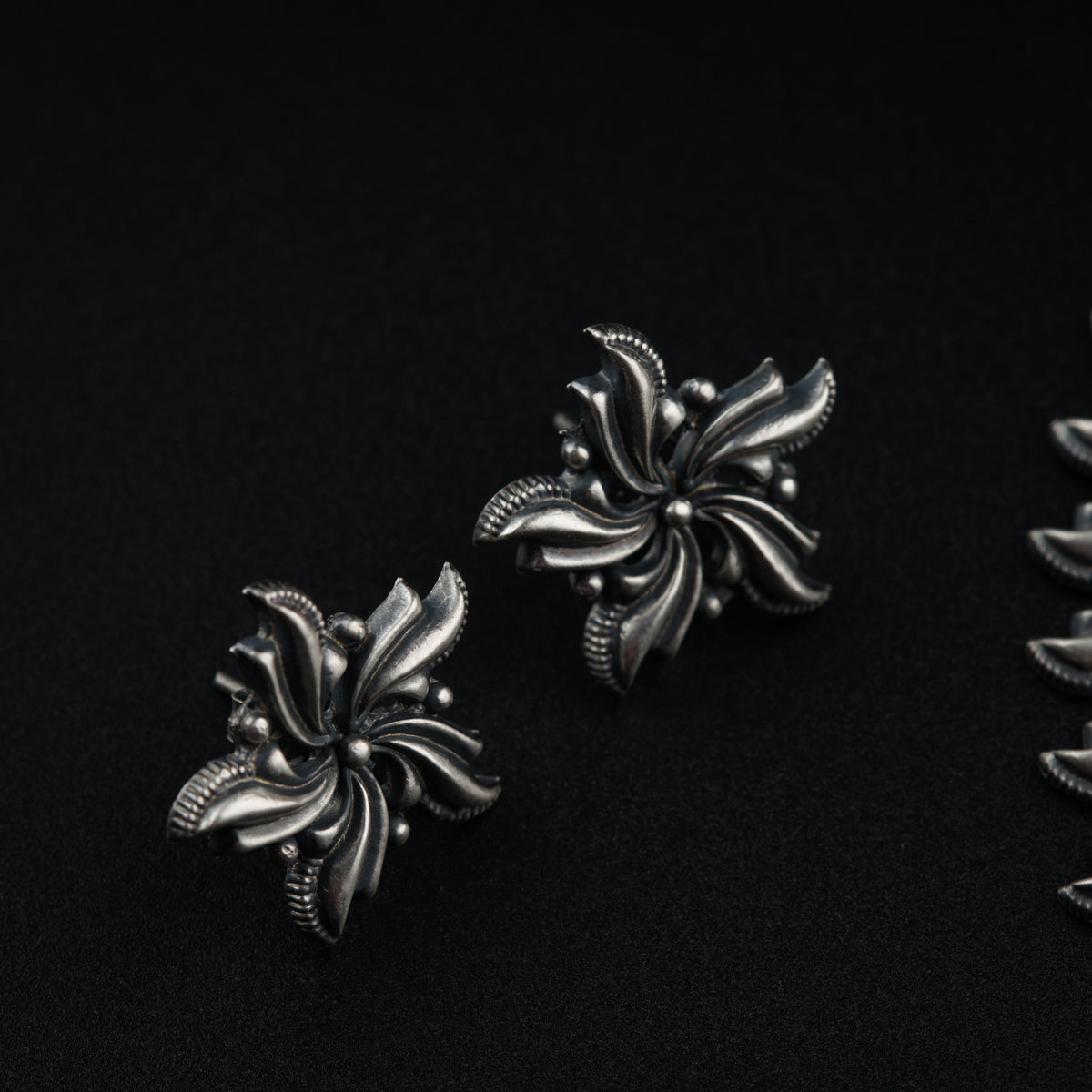 a pair of silver earrings sitting on top of a black surface