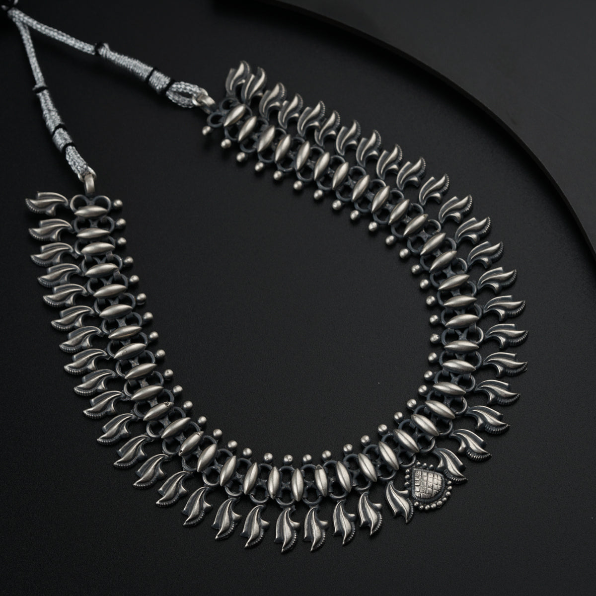 a silver necklace on a black surface
