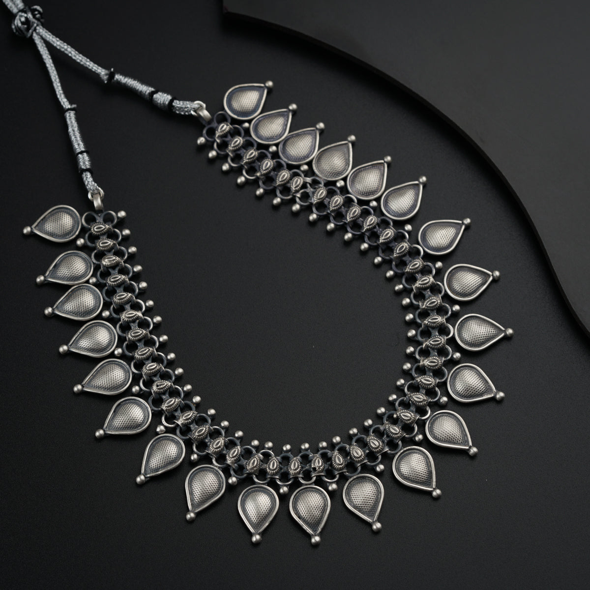 a black and silver necklace on a black surface