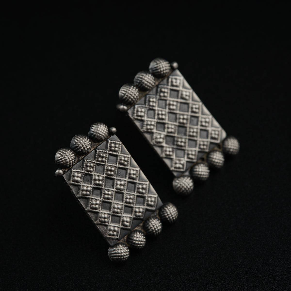 a pair of silver earrings on a black background