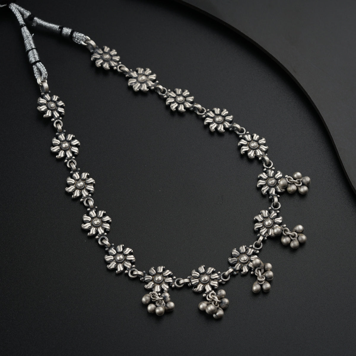 a necklace with flowers on a black surface