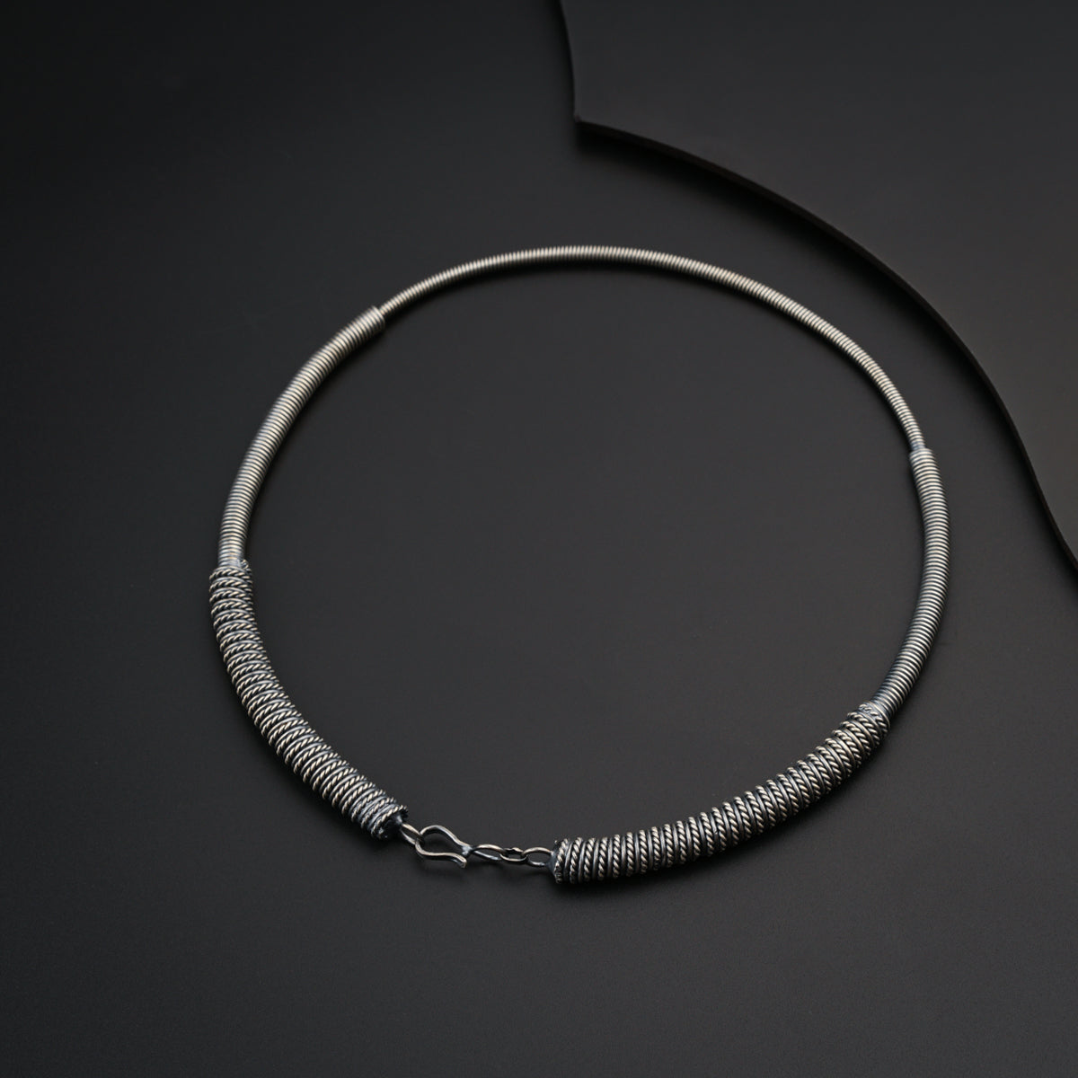 a silver necklace on a black surface