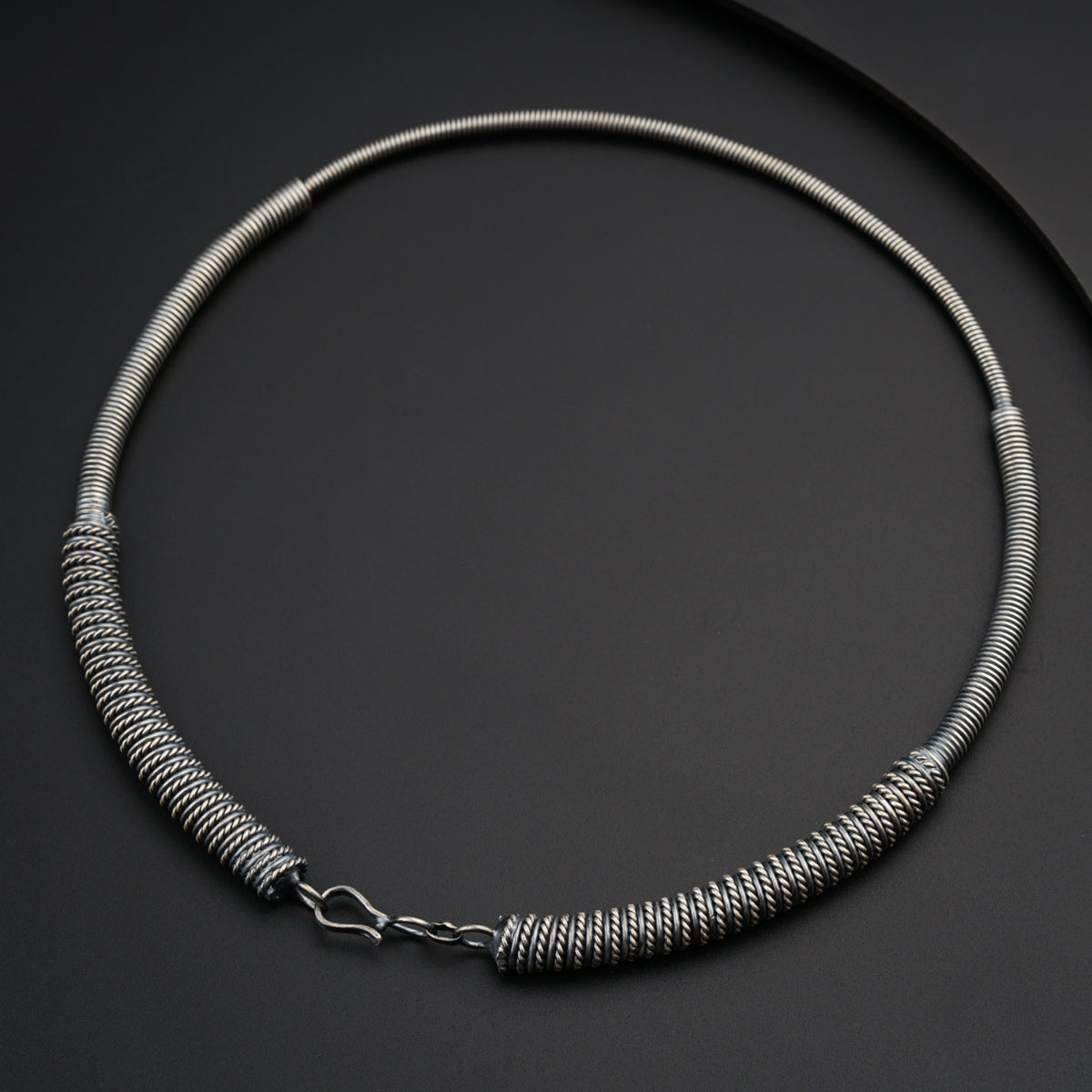 a silver necklace on a black surface