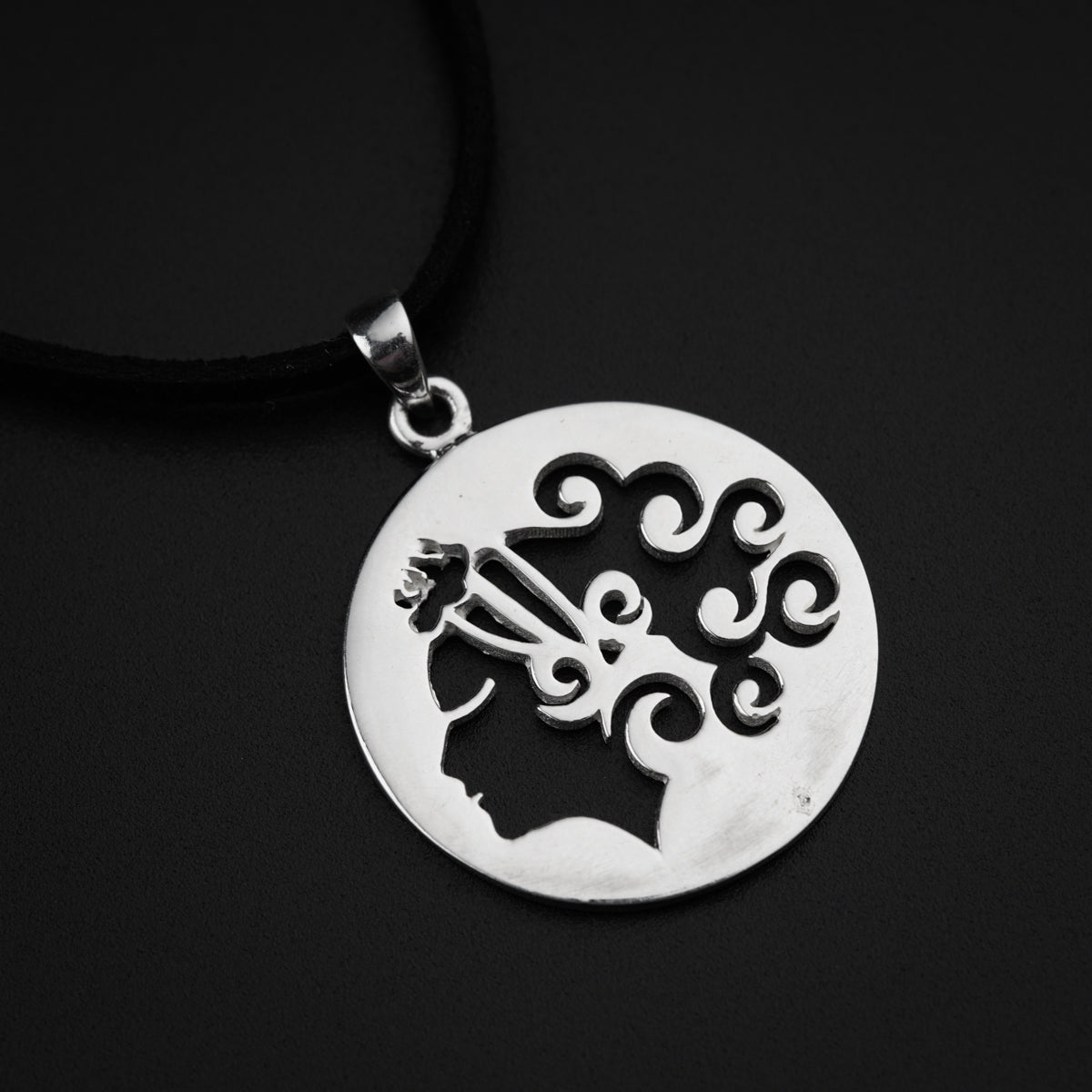 a silver pendant with a woman's head in the center