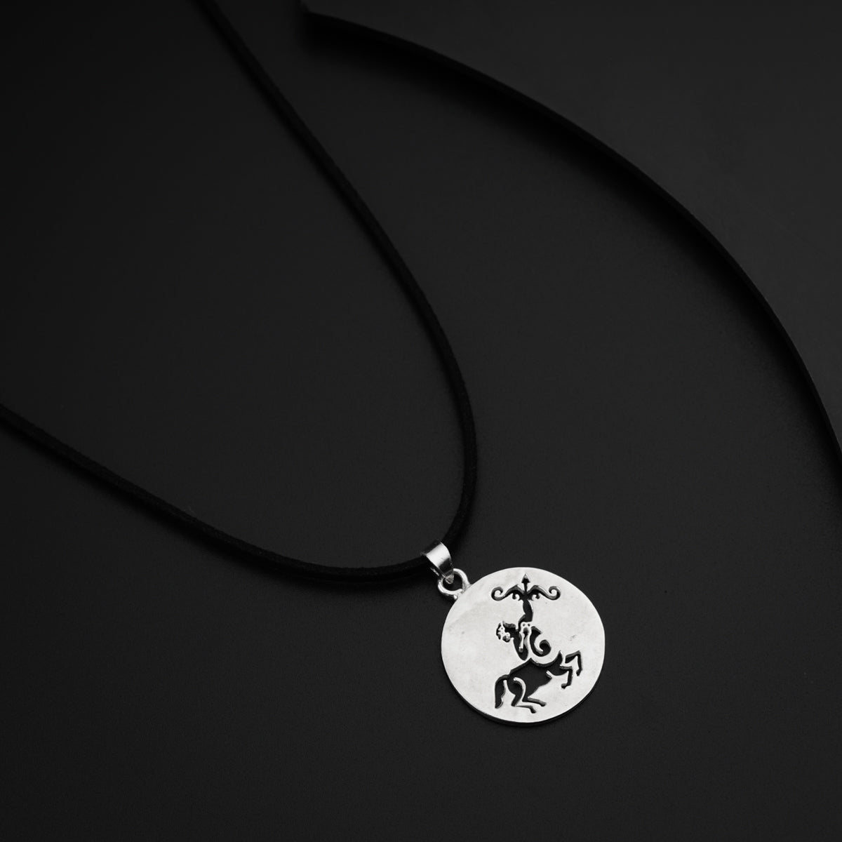 a black and white photo of a necklace with a horse on it
