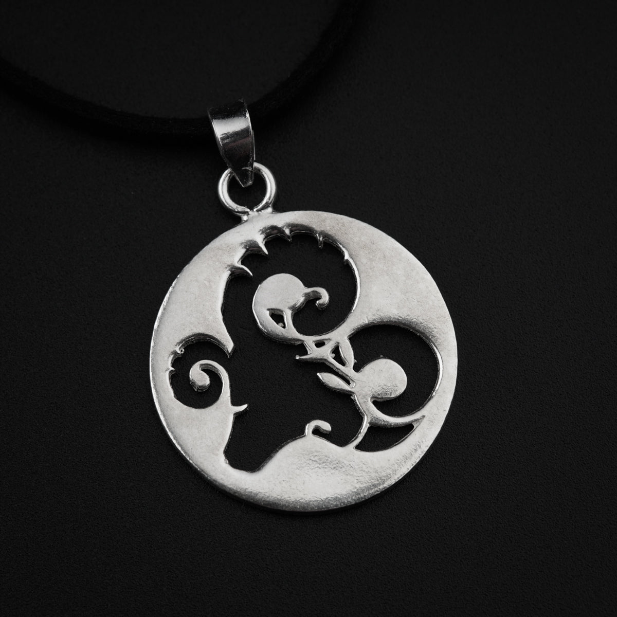 a silver pendant with a design on it