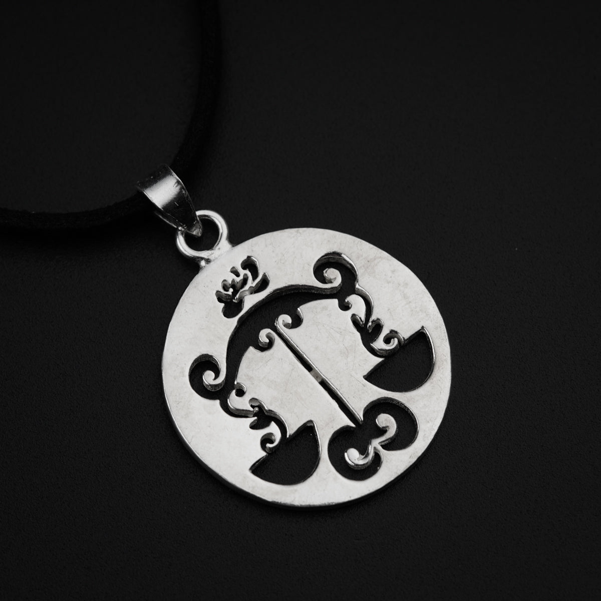 a silver pendant with a design on it