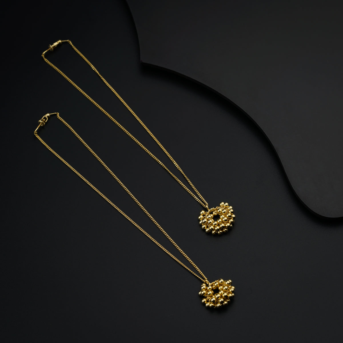 three gold necklaces on a black surface