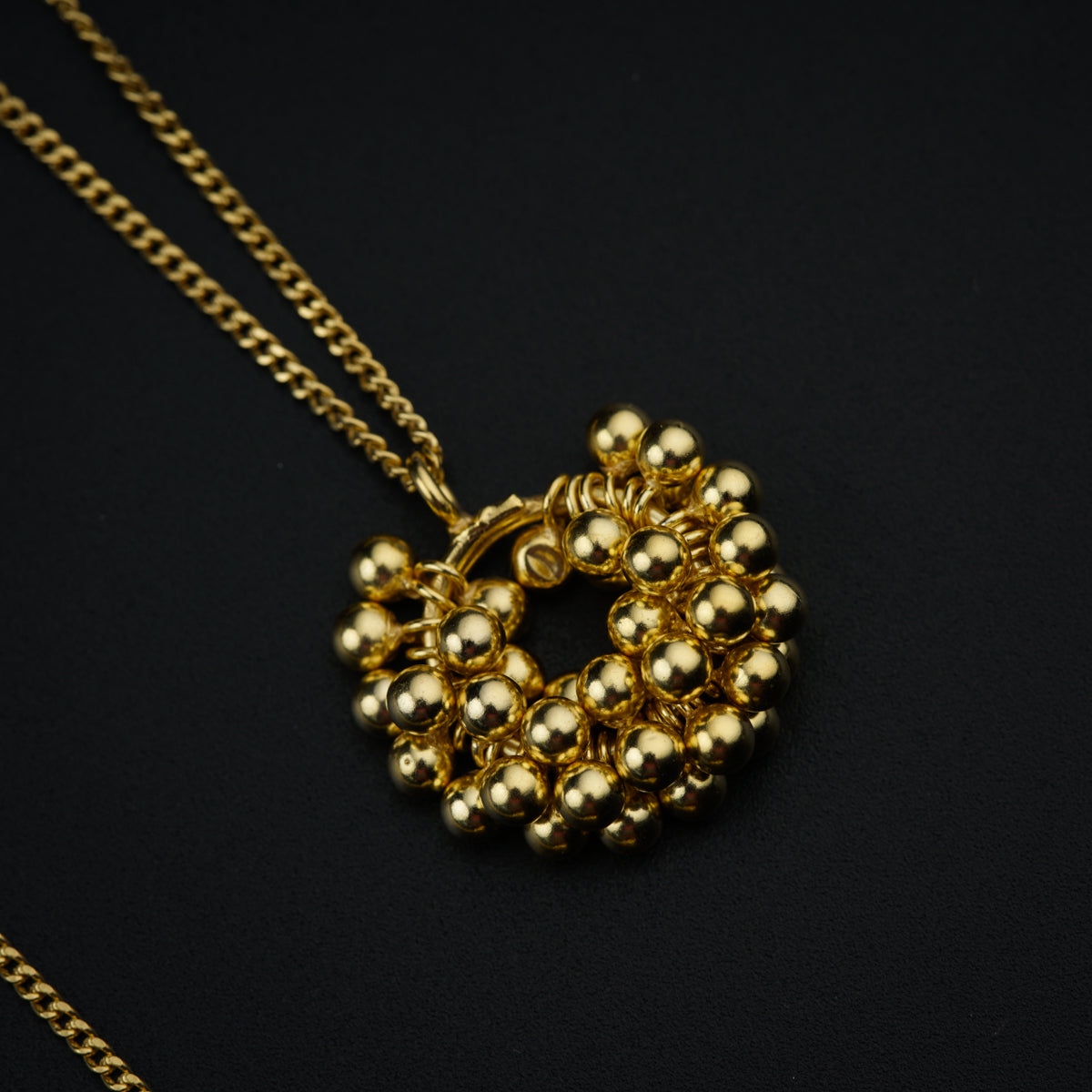 a gold necklace with beads on a black background