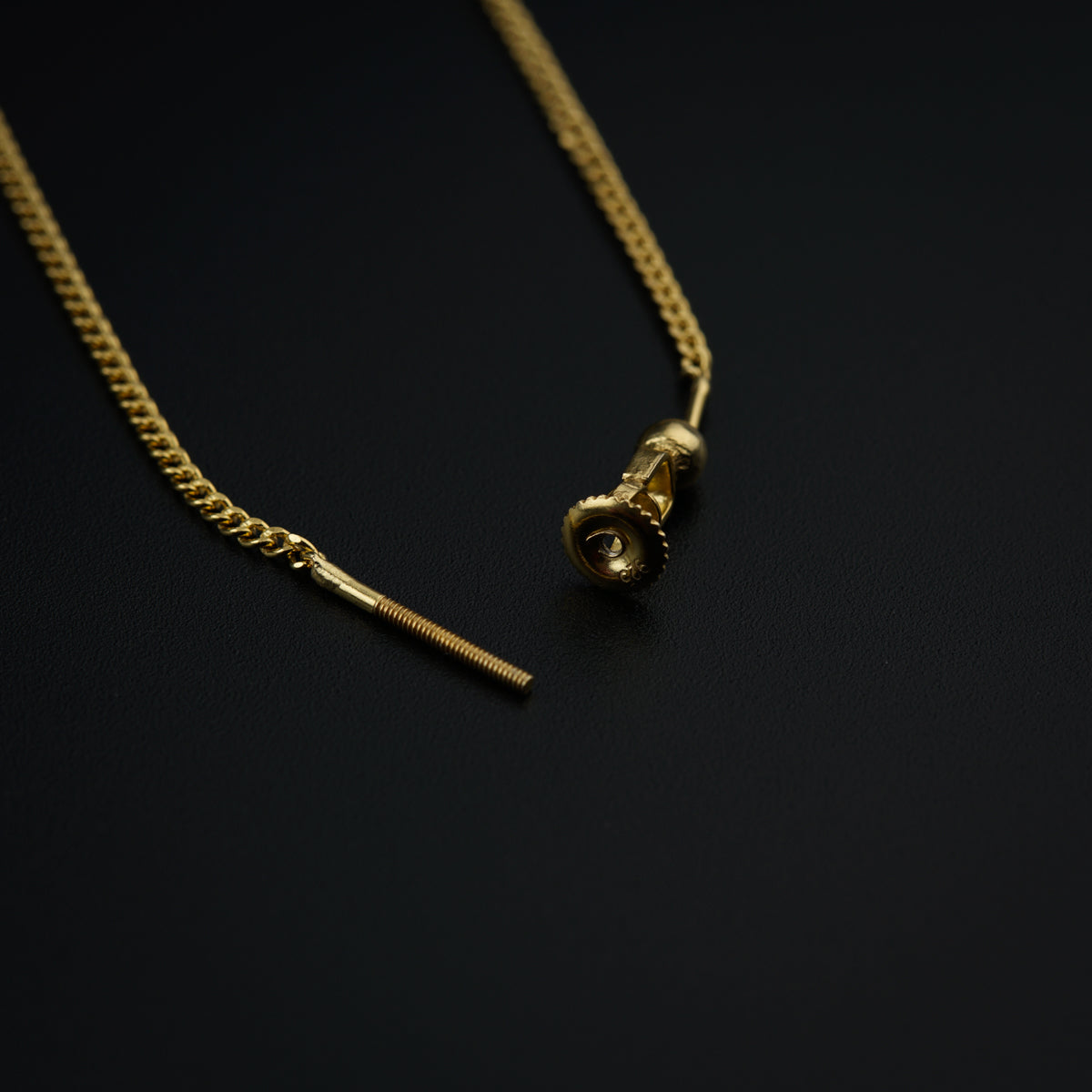 a gold necklace with a single diamond on a black surface