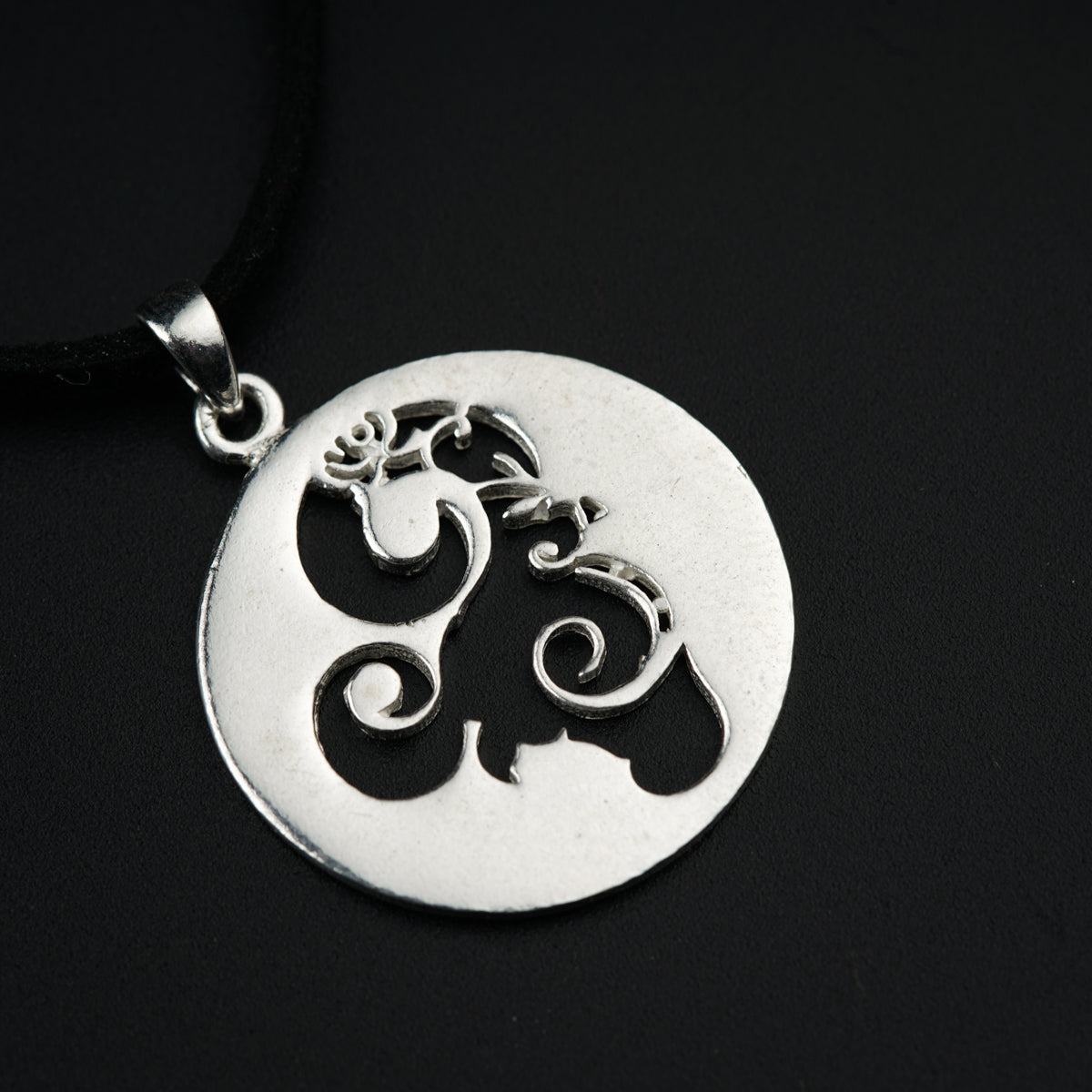 a silver pendant with an elephant on a black background