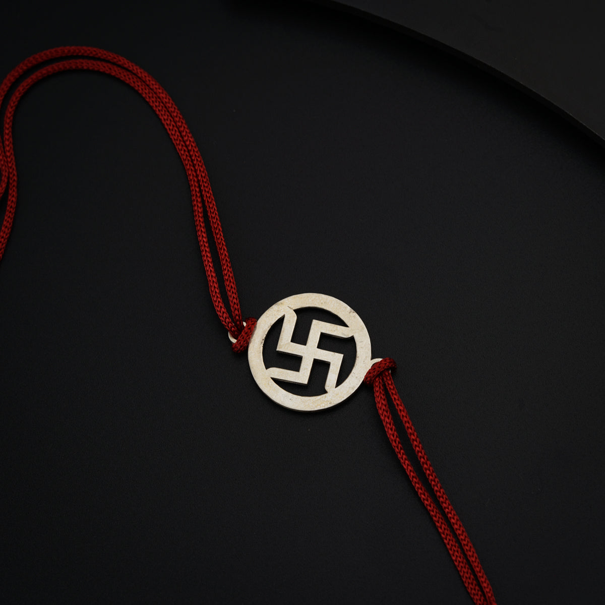 a red string with a silver pendant on it