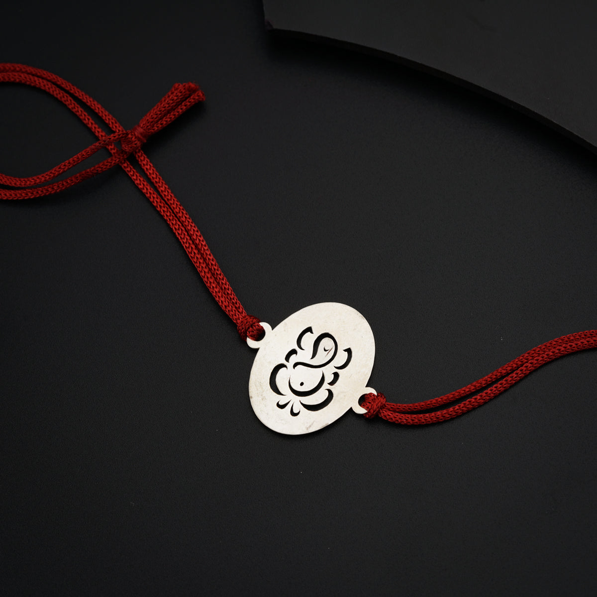 a red string with a silver pendant on it