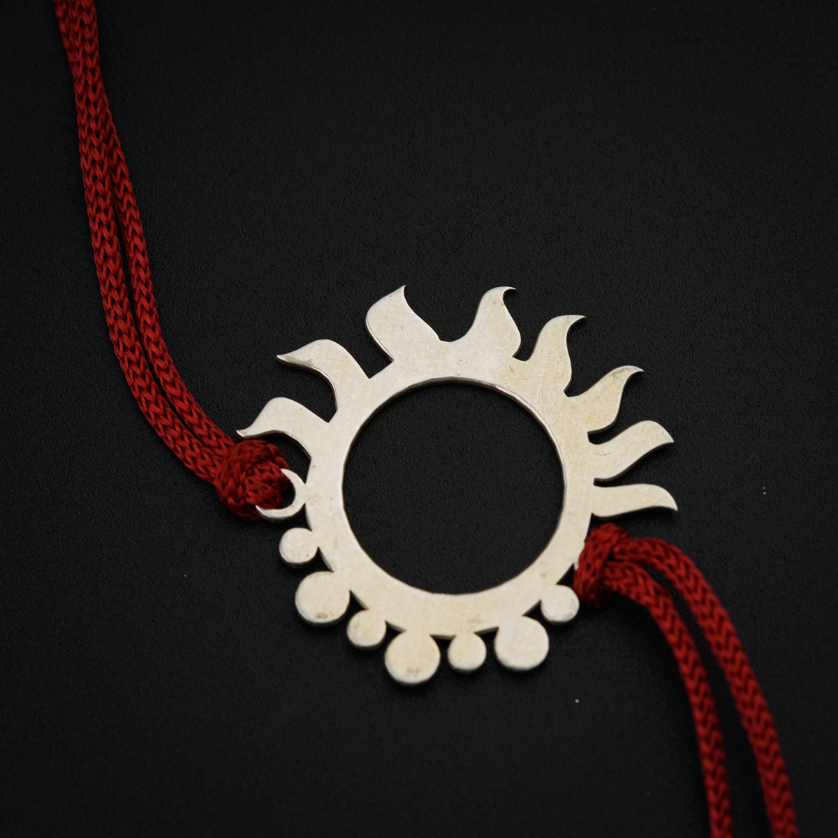a necklace with a sun design on a red string