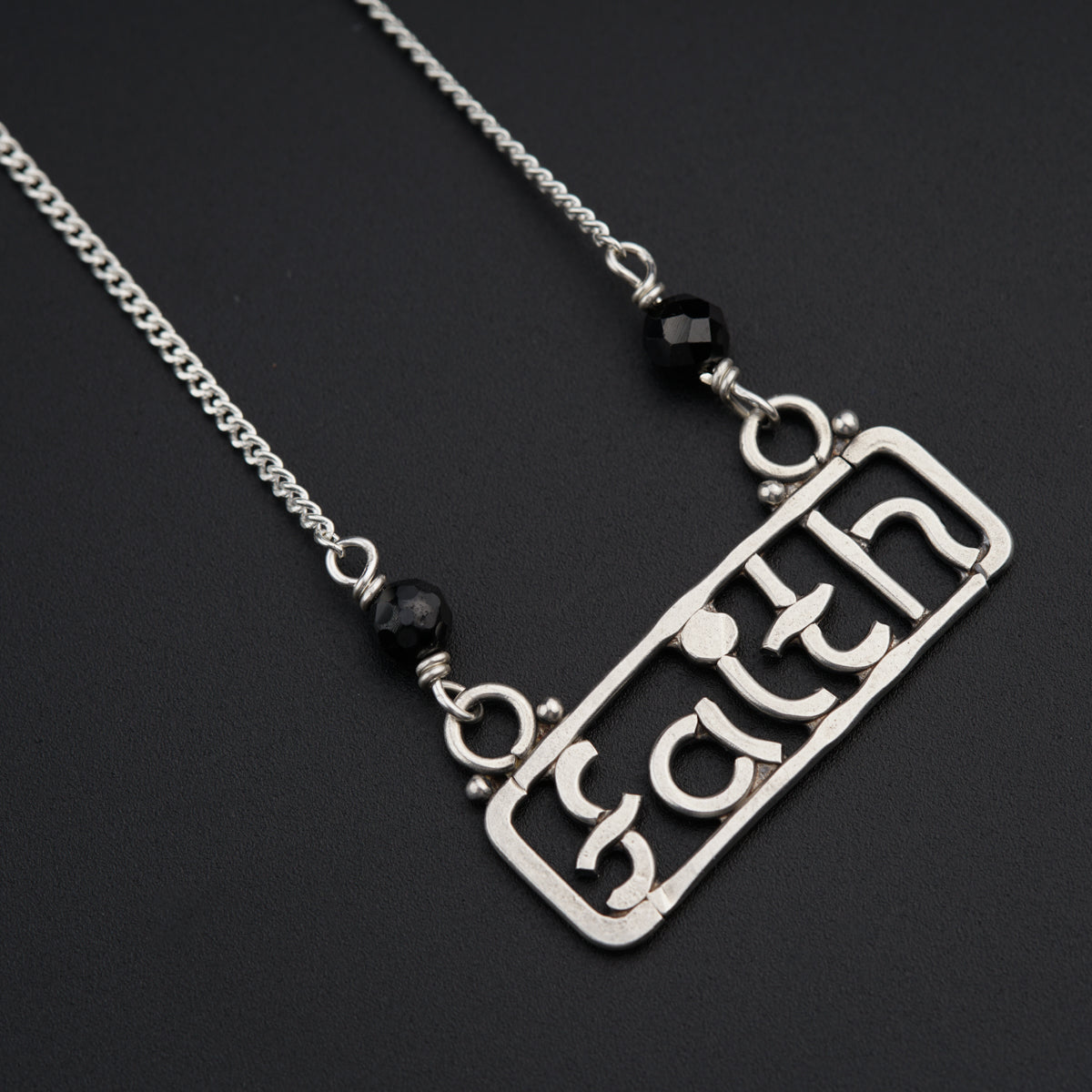 a silver necklace with a black bead hanging from it