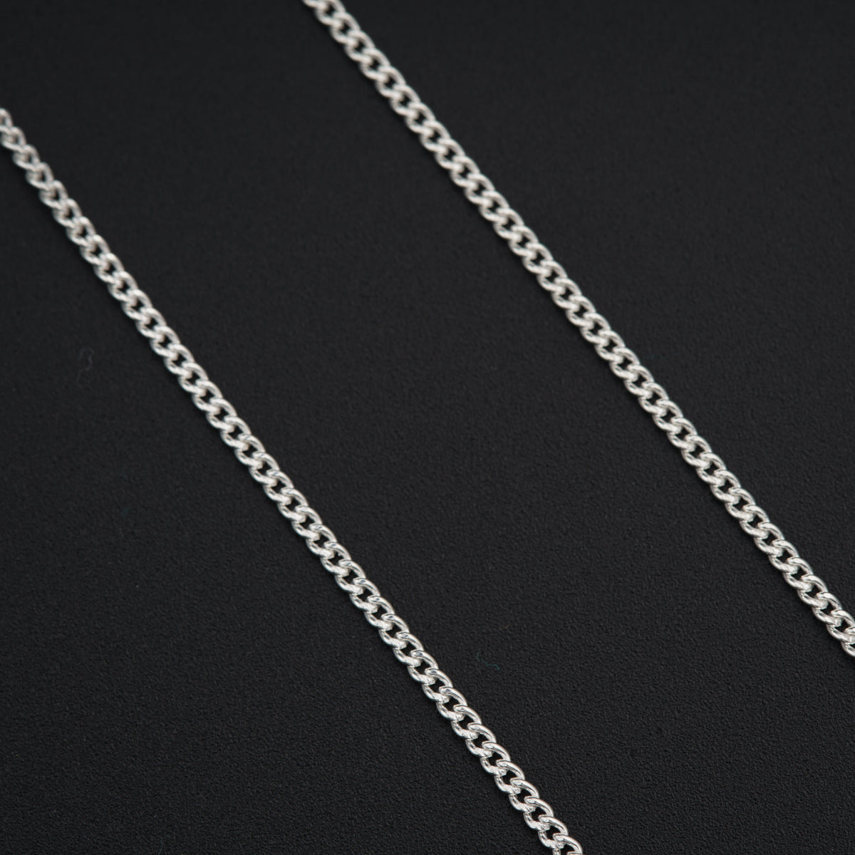 a silver chain is shown on a black surface