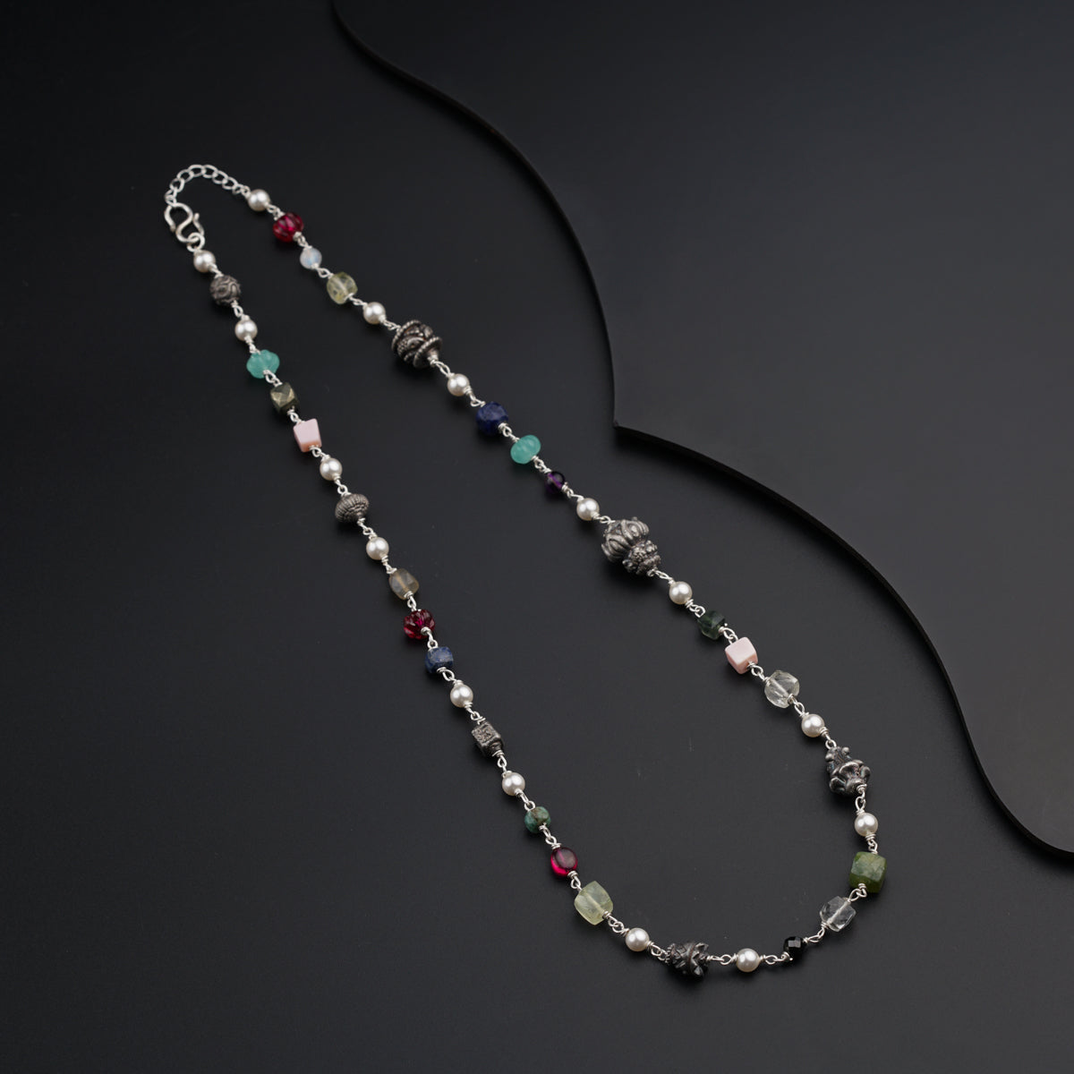 a long necklace with beads and beads on a black surface