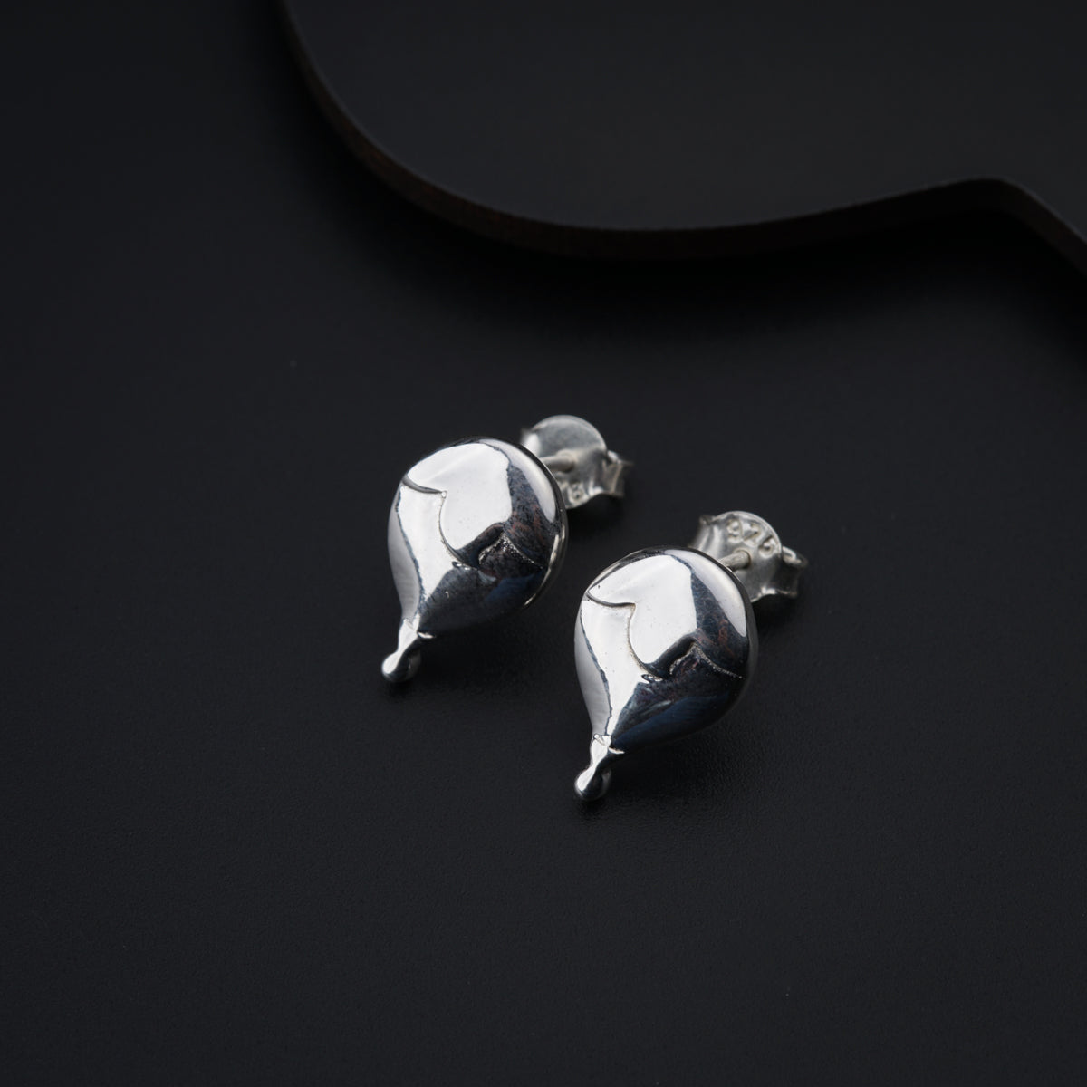 a pair of silver earrings sitting on top of a black surface