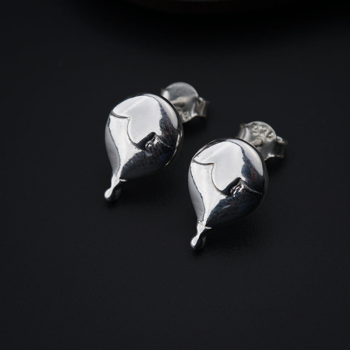 a pair of silver earrings sitting on top of a table