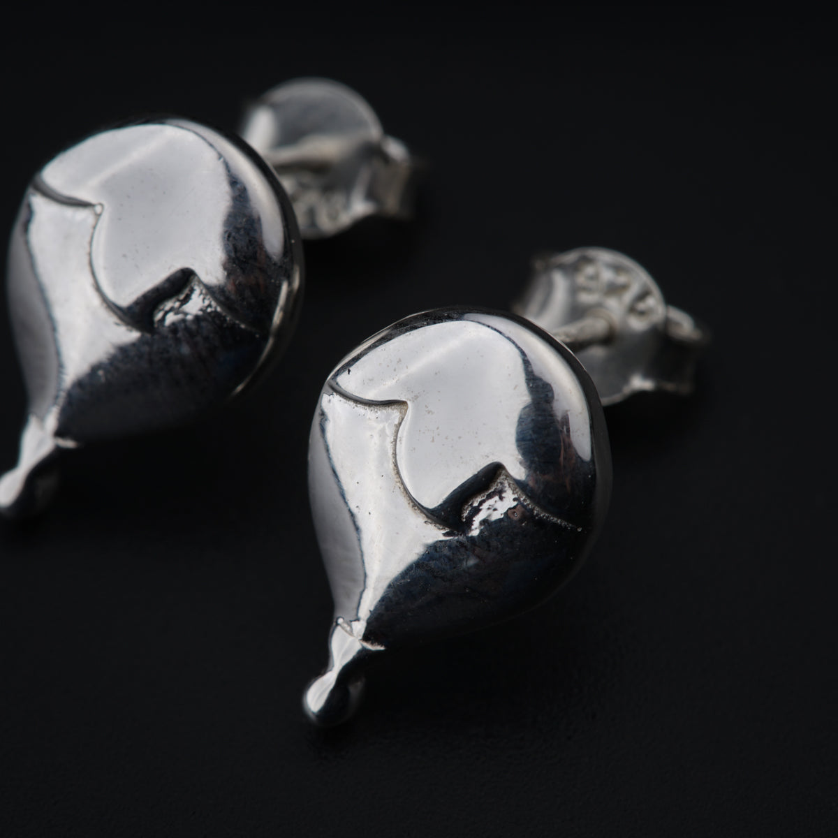 a pair of silver cufflinks on a black surface