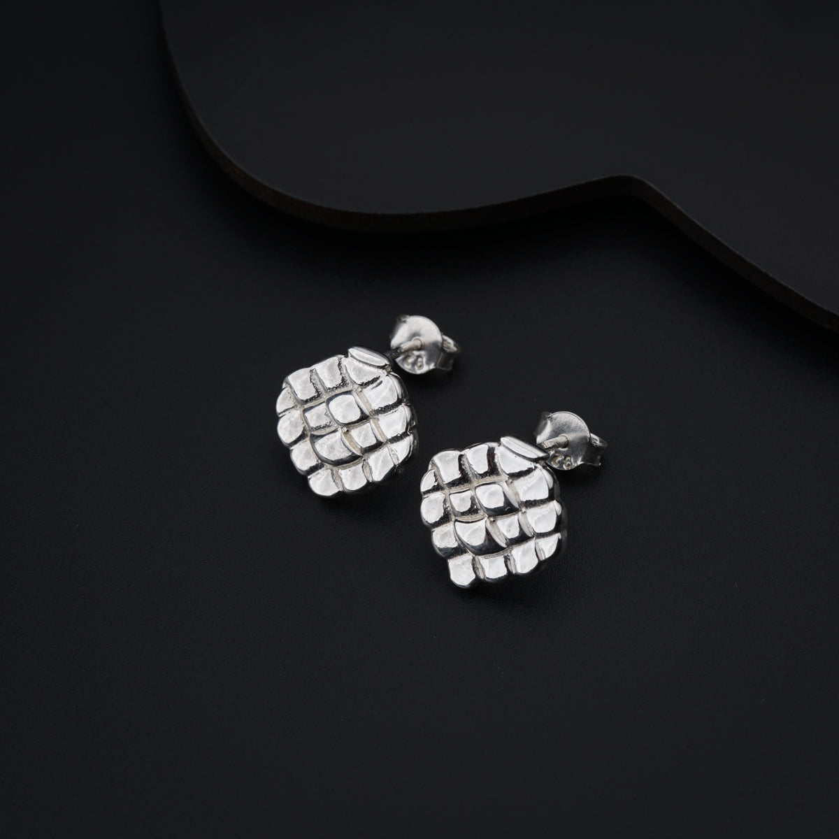 a pair of silver earrings sitting on top of a black surface