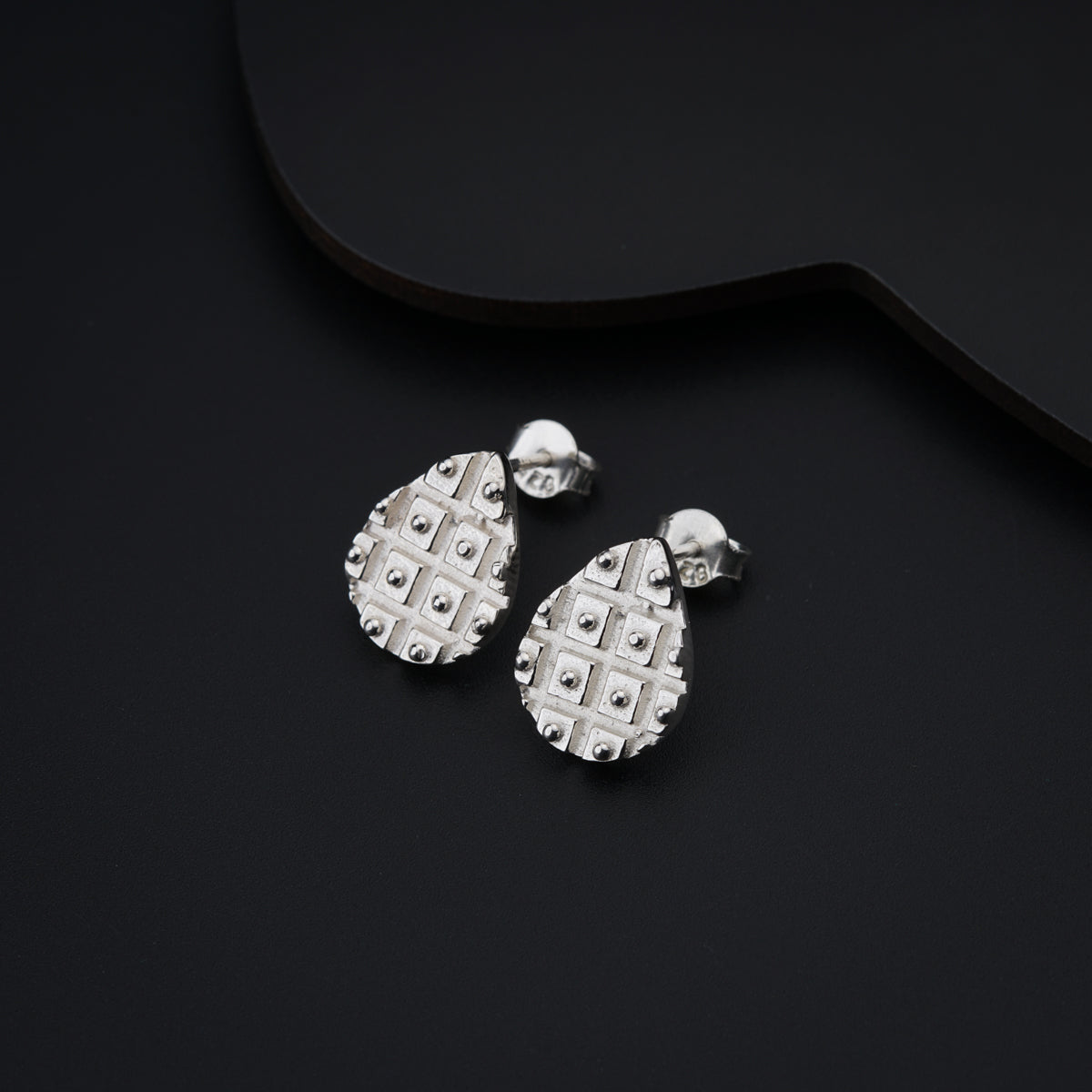 a pair of earrings sitting on top of a black surface
