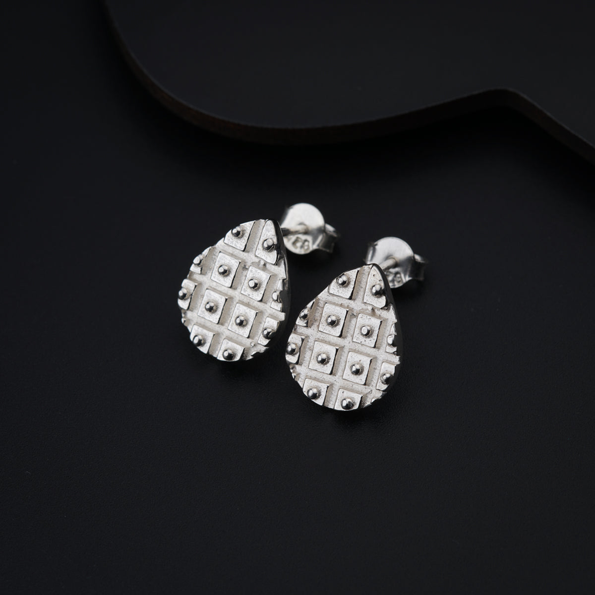 a pair of earrings sitting on top of a black surface