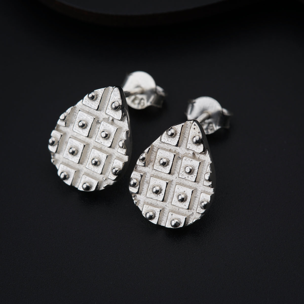 a pair of silver earrings on a black surface