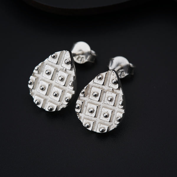 a pair of silver earrings on a black surface
