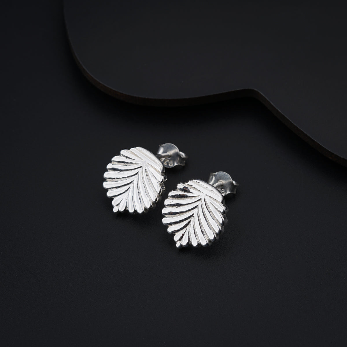 a pair of silver earrings on a black background