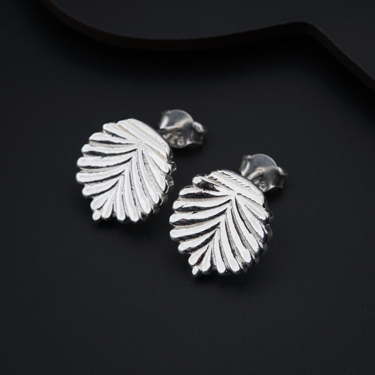 a pair of silver earrings sitting on top of a black surface