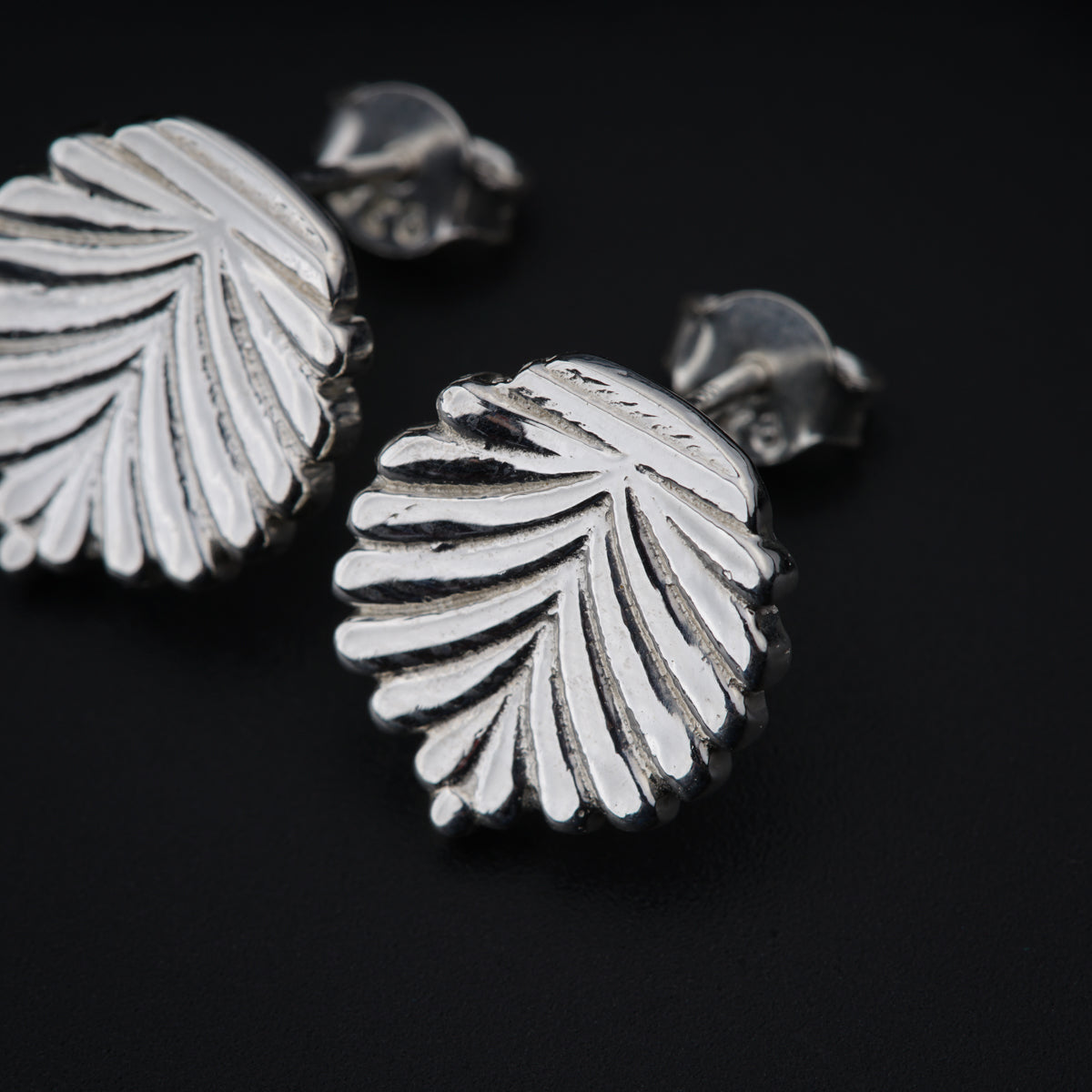 a pair of silver earrings on a black surface