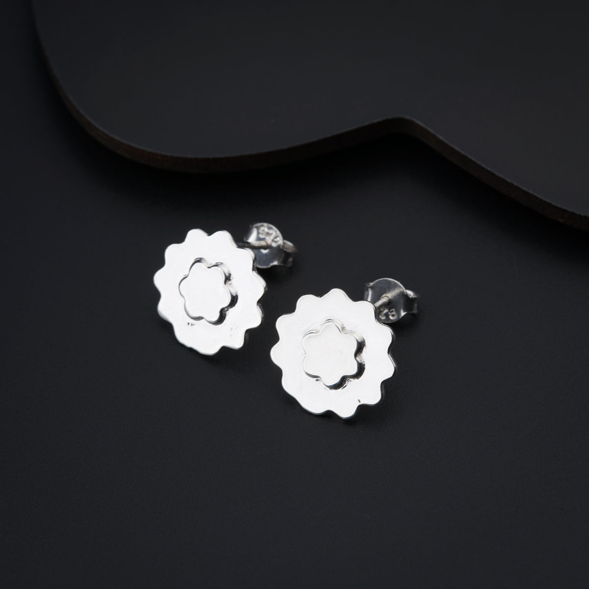 a pair of silver flower earrings on a black background