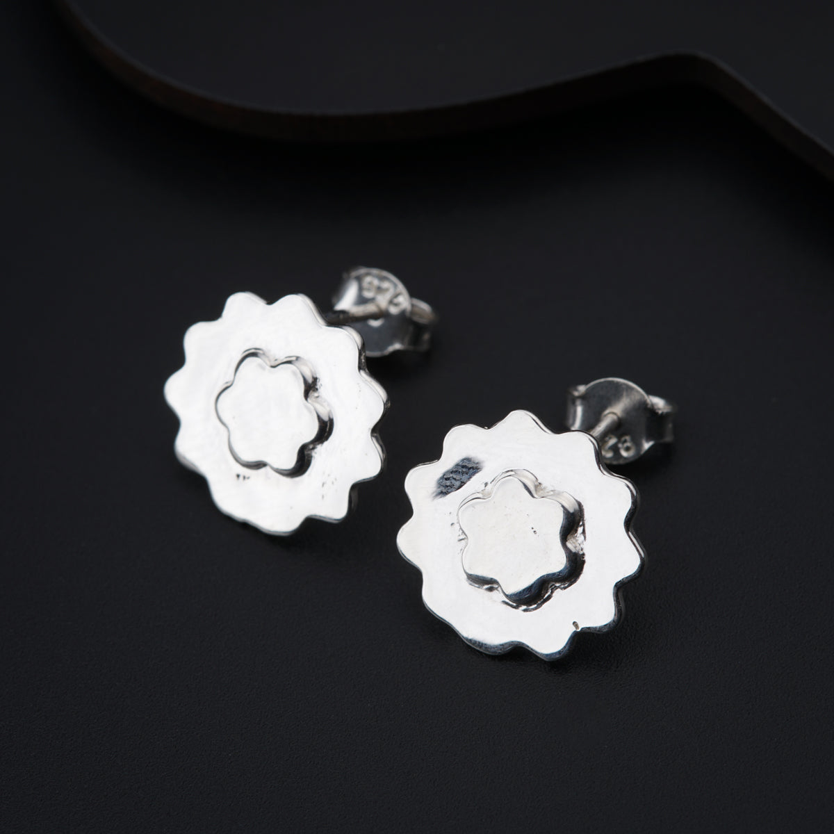 a pair of silver earrings on a black surface