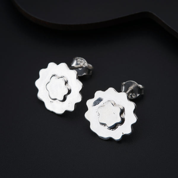 a pair of silver earrings on a black surface
