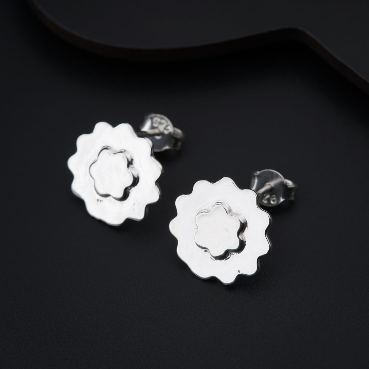 a pair of silver flower earrings on a black background