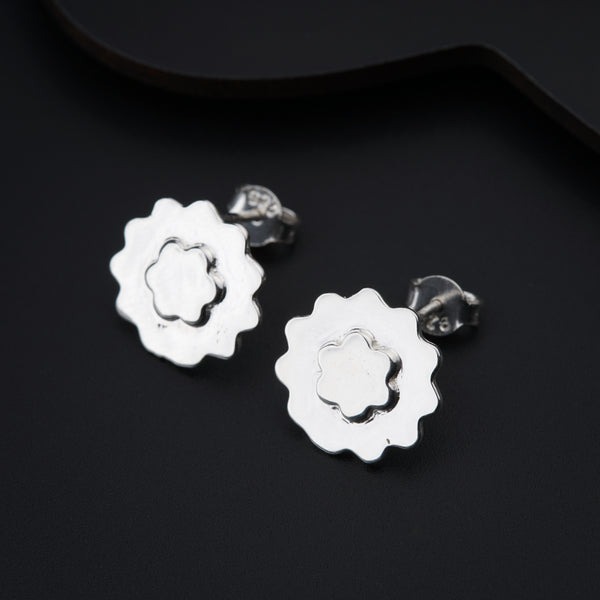 a pair of silver flower earrings on a black background